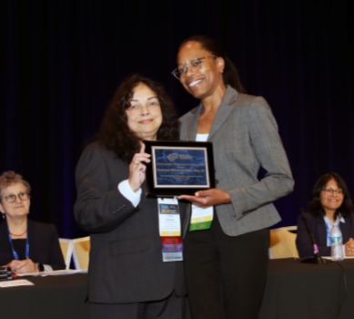 Recipient being presented with an award on stage, smiling for a photo with the presenter.